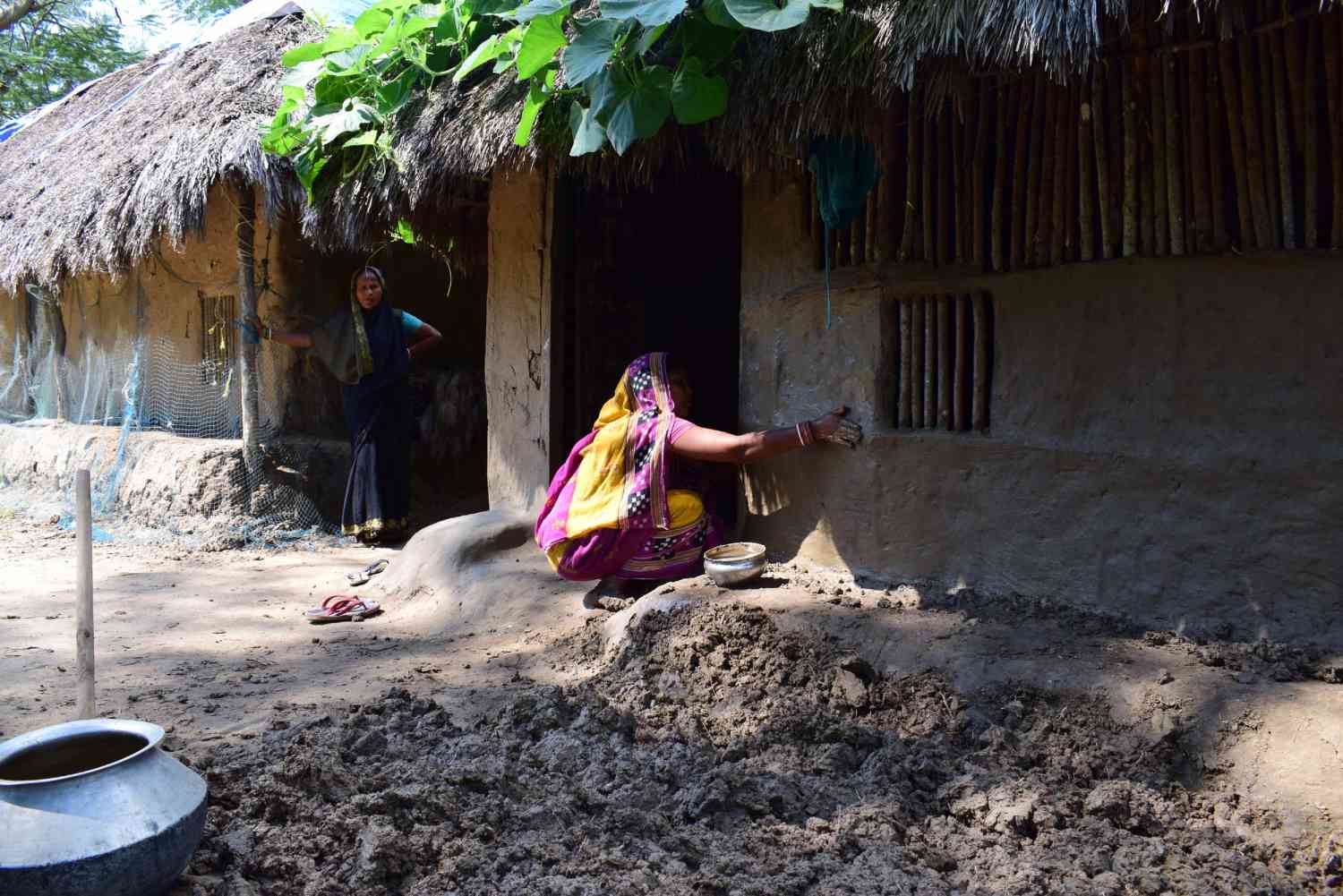woman repairing a mud house