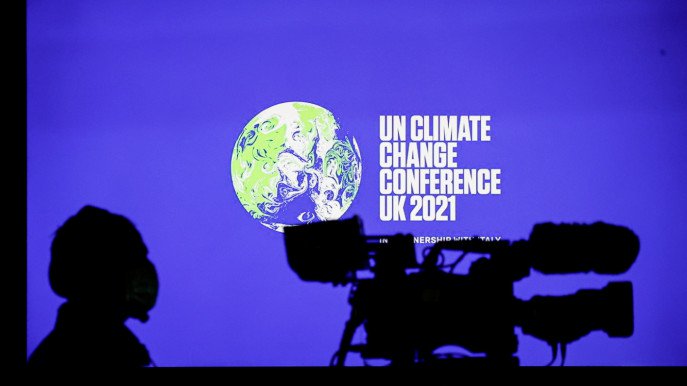 A cameraman sits in front of a screen displaying COP26 logo during a news conference at the UN Climate Change Conference (COP26), in Glasgow, Scotland, Britain, November 5, 2021. Photo : Reuters