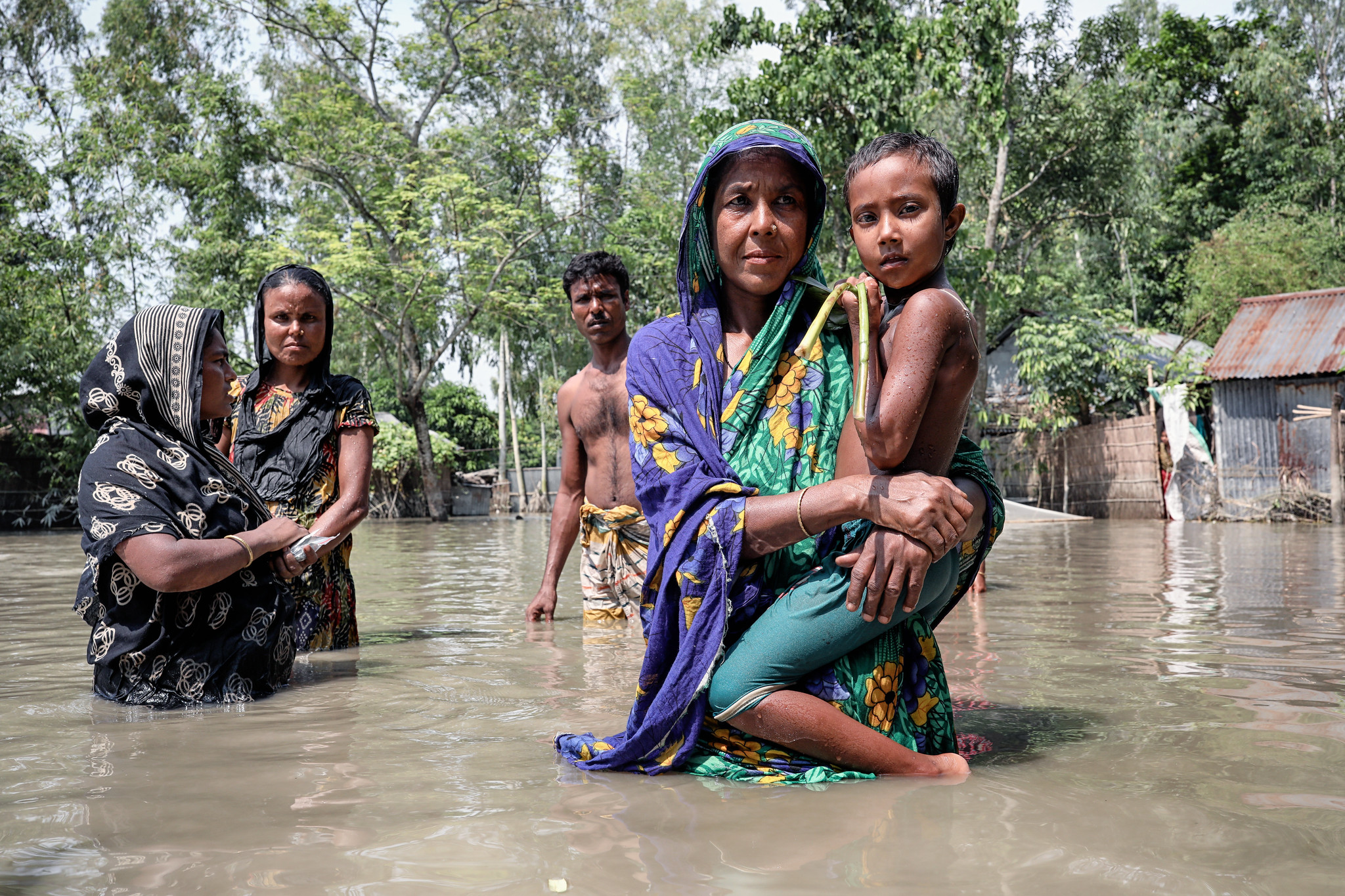 women with children standing in floodwater