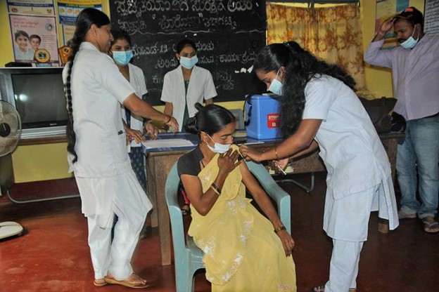 Woman in yellow sari receiving vaccination 