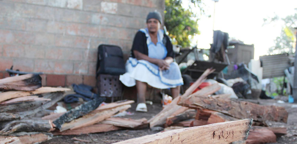 a woman sits near a pile of firewood