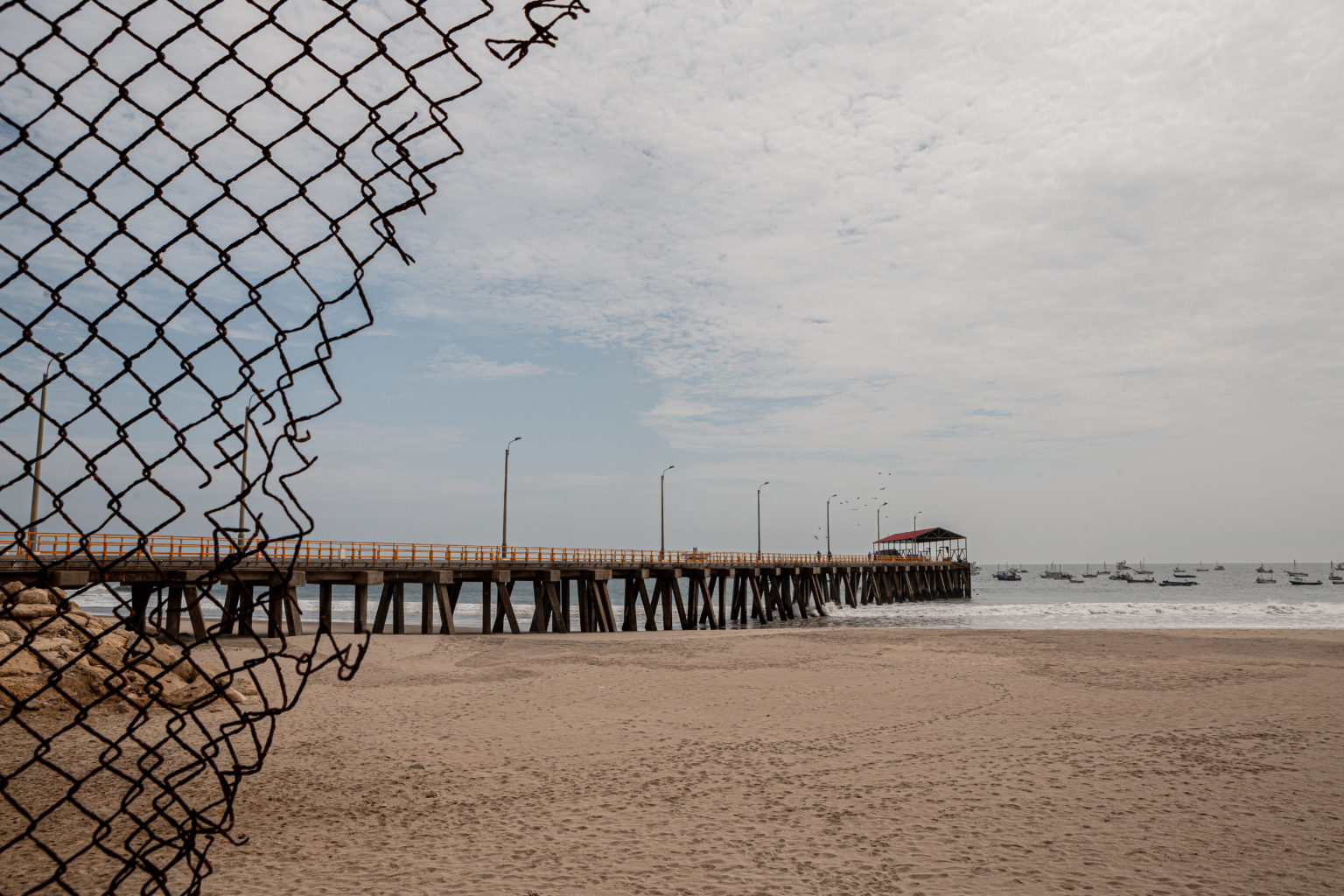 A beach through a wire fence