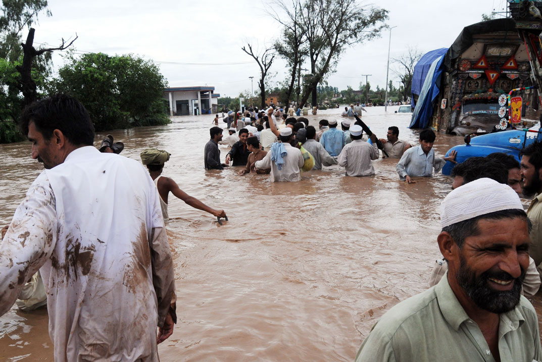 people try to flee a flooded street in Pakistan