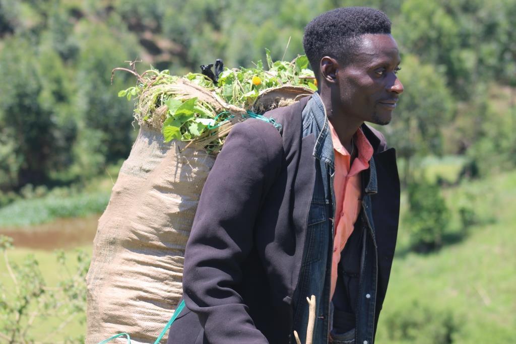 A man carries a sack of fresh vegetables