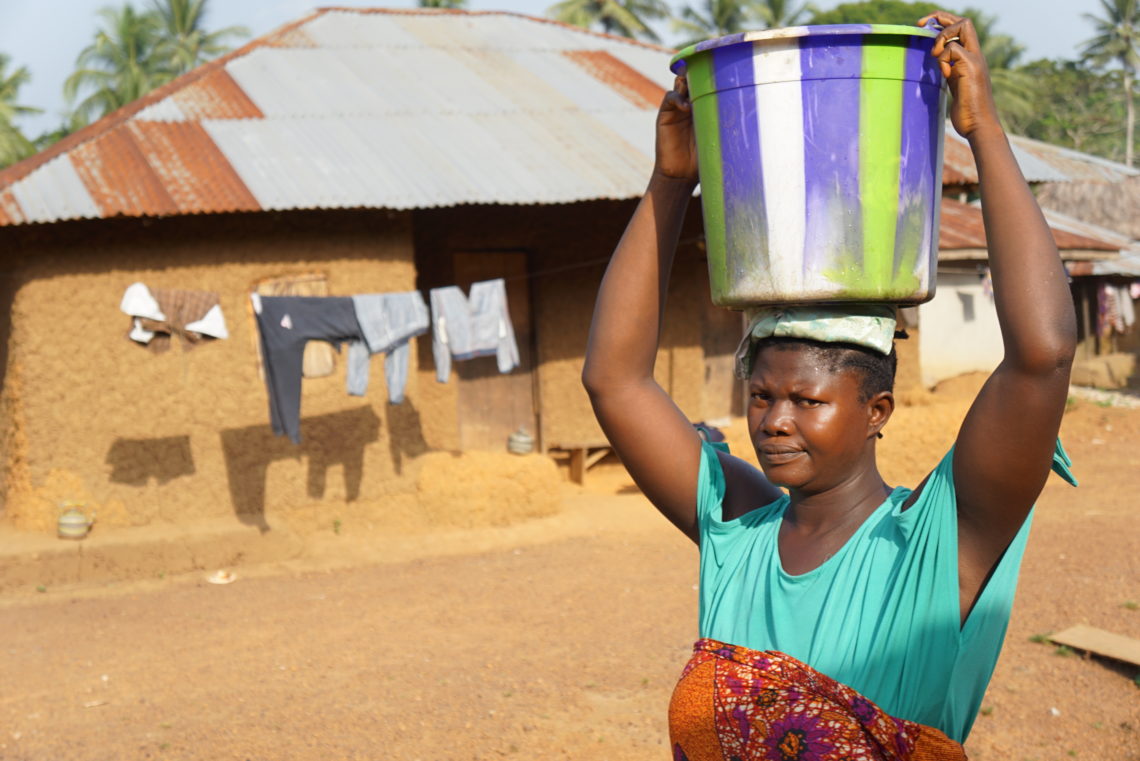 A woman carries a bucket on her head