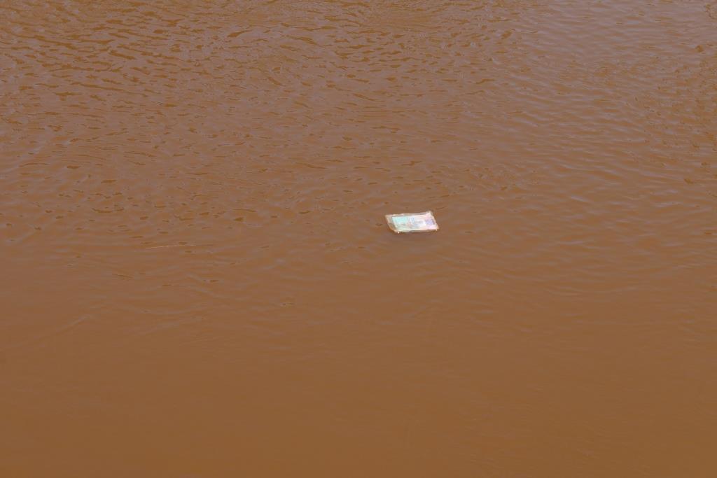 Rubbish floats on the brown waters of the Rwizi