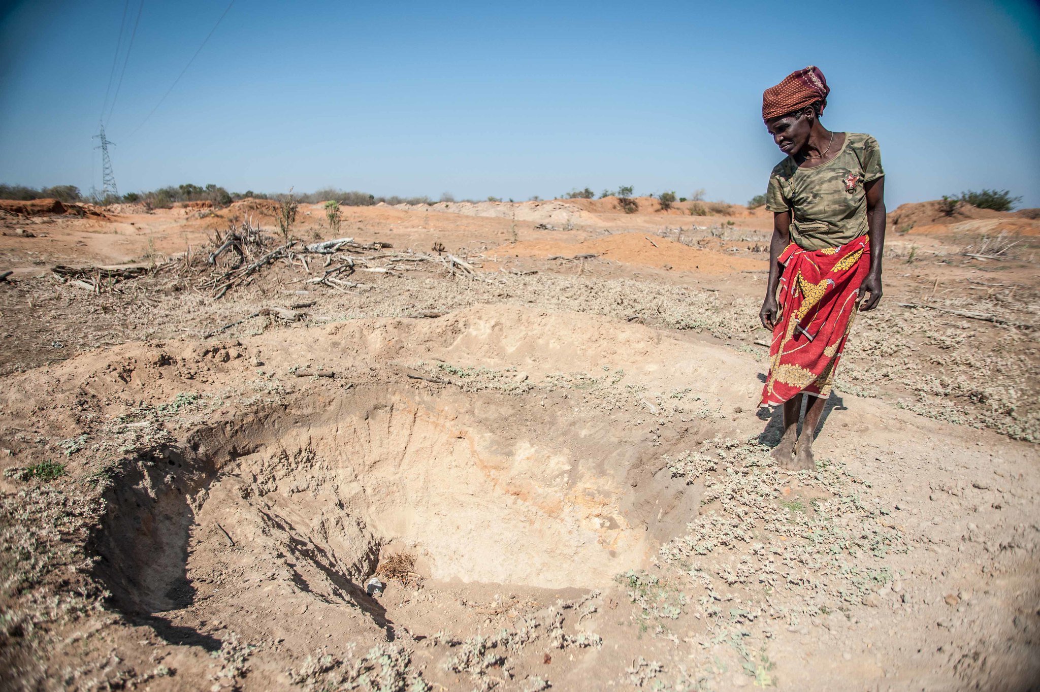 a woman stands next to a dry water hole