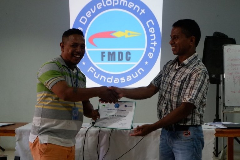Francisco De Silva Gari hands over certificate of attendance to a journalist Eduardo T. Exposto from Radio Comunidade Liquica