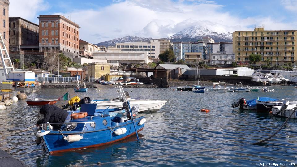 a boat in the small port of Torre del Greco in Italy, with mountains in the background
