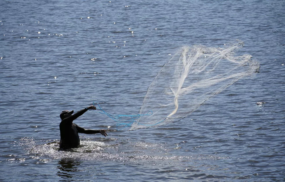 A man throws a fishing net into water
