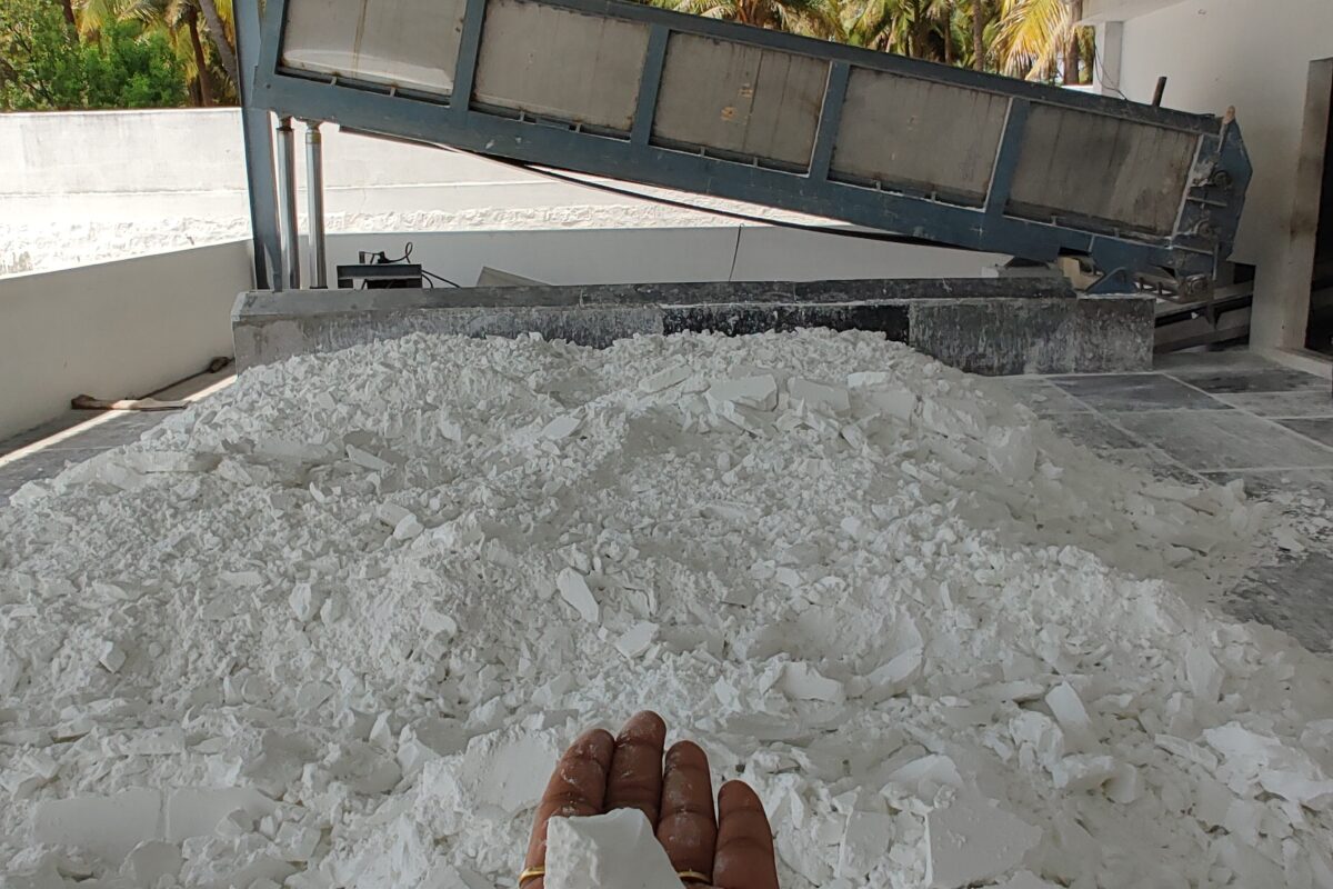 a hand holding up a creamy powder in piles on the floor