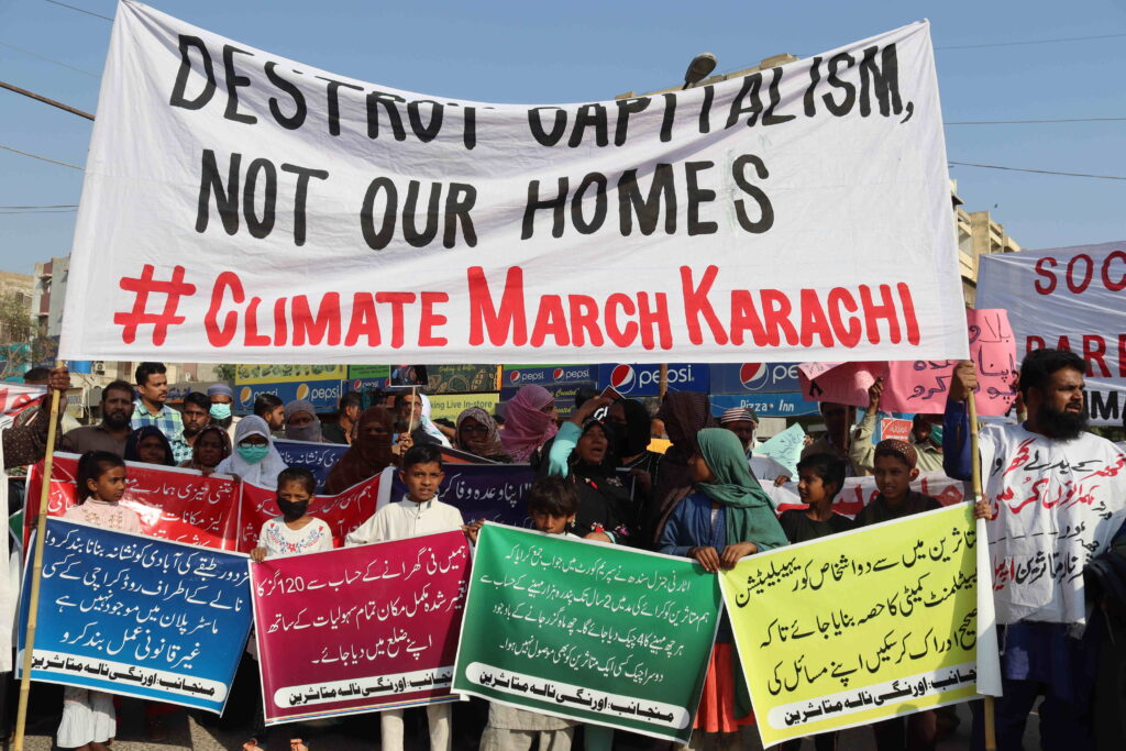 women and children holding signs at a climate protest in Pakistan