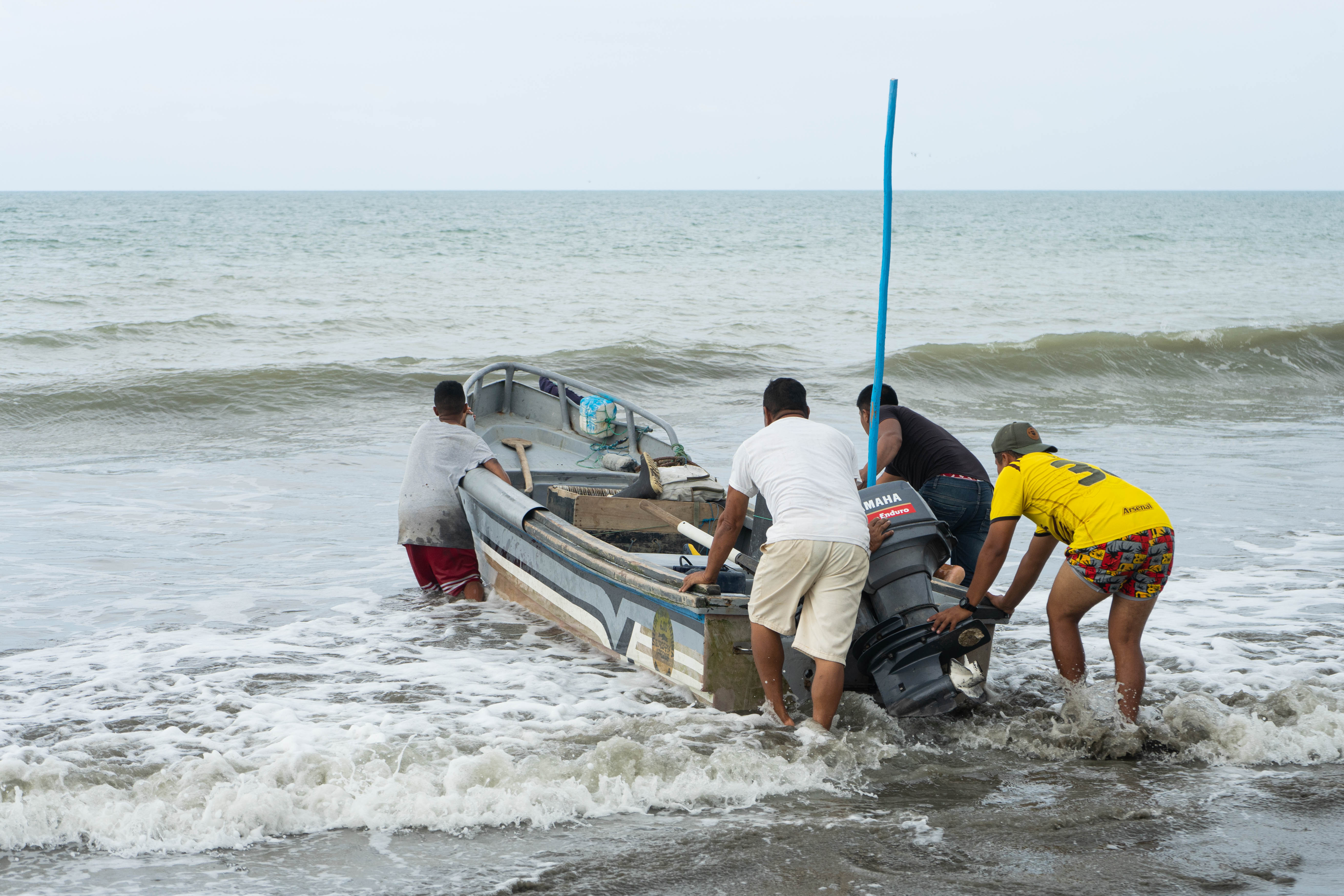 men pushing a boat into water