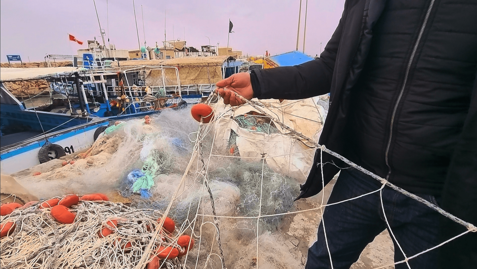 A fisherman showing a net on his boat in a port