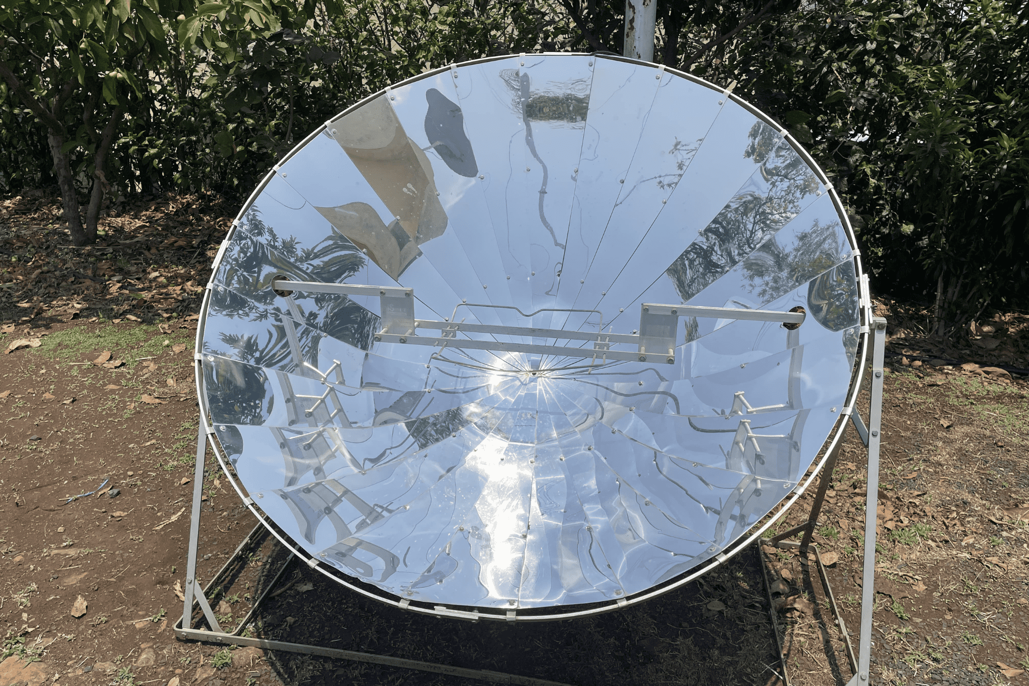 A concave, reflective dish is installed in the middle of a green patch.