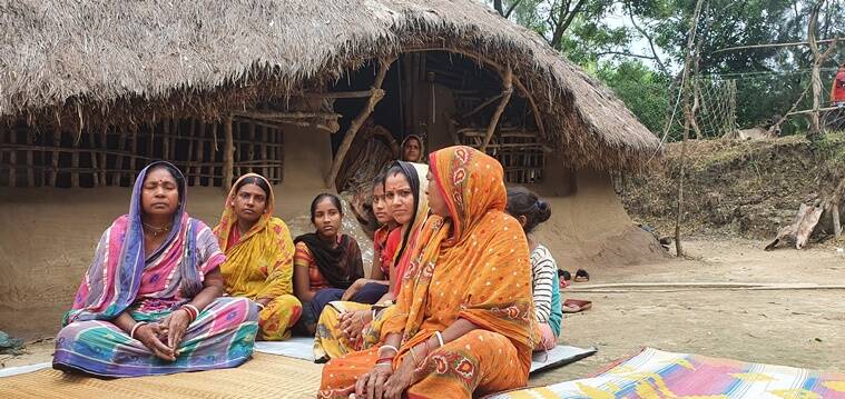women seated near a mud hut