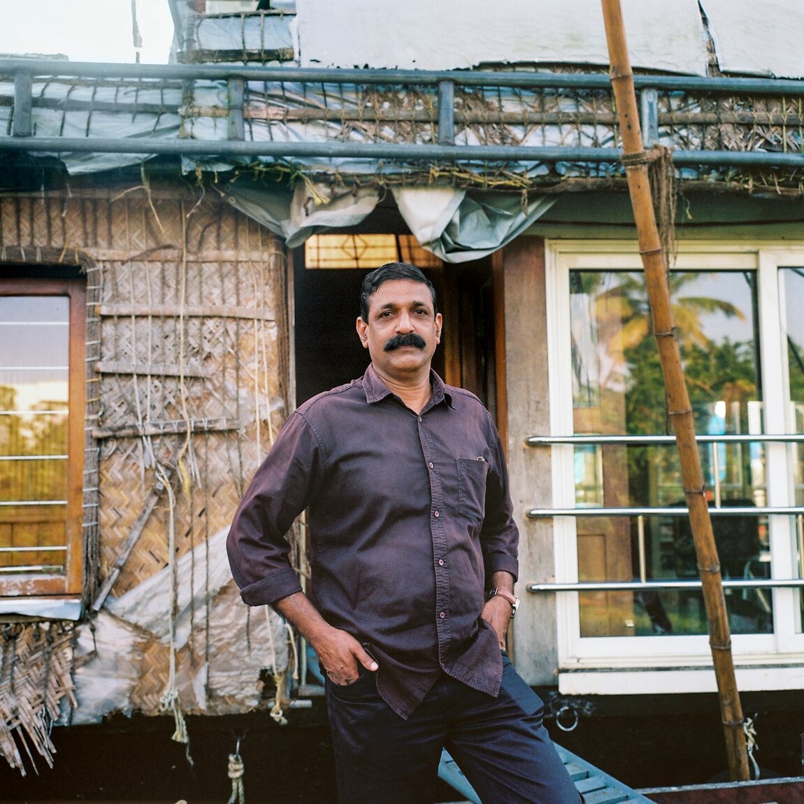 Sajan Varghese, a houseboat owner and operator, poses with his kettuvallam in Alleppey.