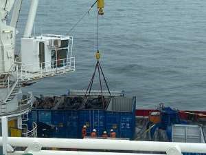A crane lifts a container out of the ocean