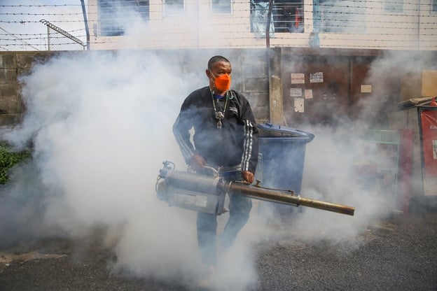 A man wearing an orange mask holds mosquito fogger