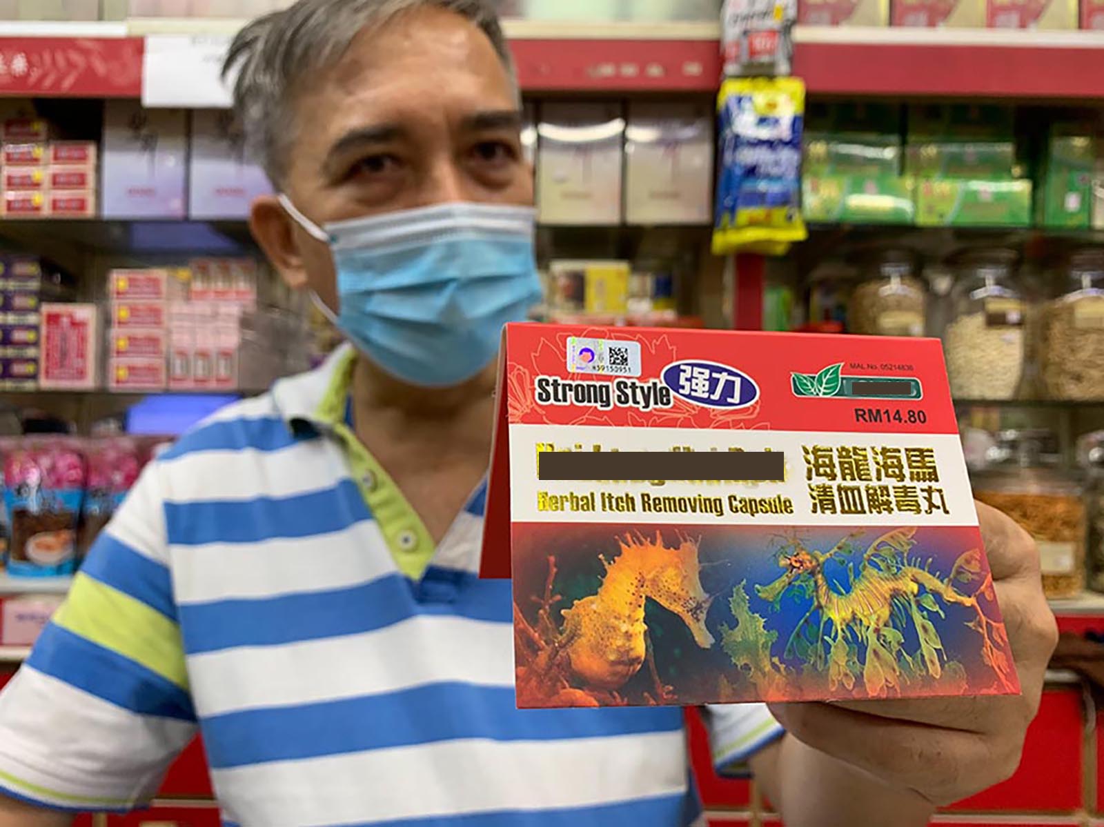  a masked man holds up traditional chinese medicine which uses seahorse as an ingredient.