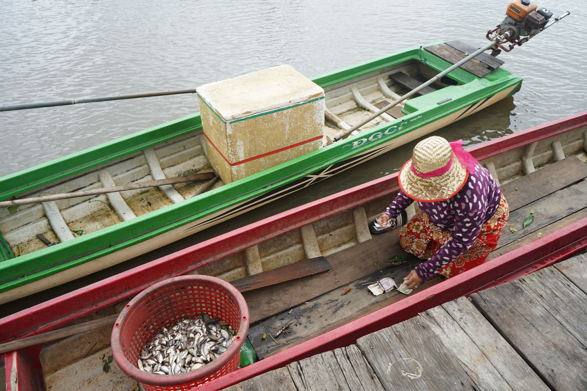a woman selling fish from a wooden boat
