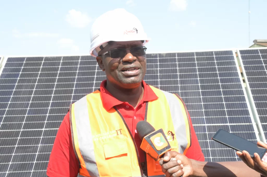 Julius Motaroki standing in front of solar panel addressing the media at the Kipkebe solar power station