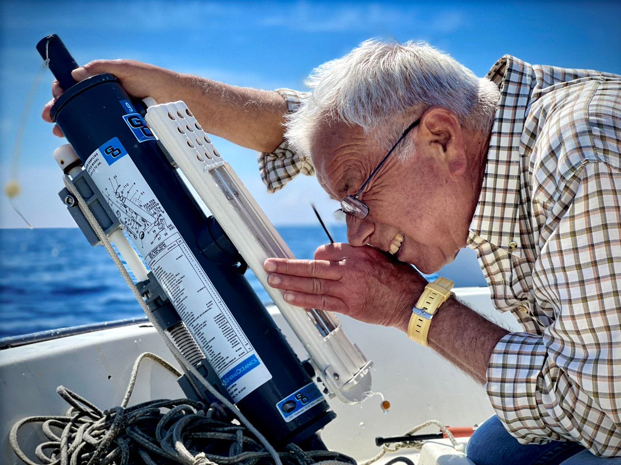 a man looking into a Nansen bottle on a boat