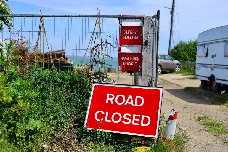 The entrance of Malcolm Newell’s road that goes all the way to the cliff. The site is still at high risk of erosion. Newell and his neighbours have been forced to evacuate since the cliff collapse in 2020 [Gaia Lamperti/Al Jazeera]