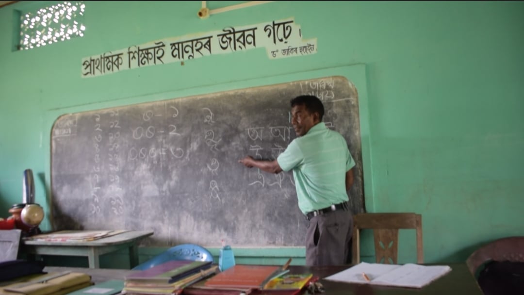a teacher pointing to a blackboard.