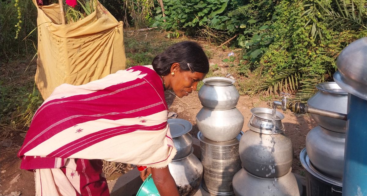 A woman bends over metallic jugs for water.