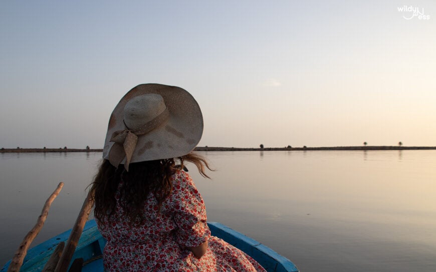 woman with a hat on a boat in the sea at sunset