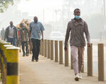 pedestrians walking along a busy road under a hazy sky in Nairobi