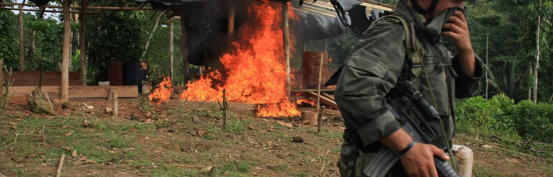 a policeman walking away after setting fire to a coca lab