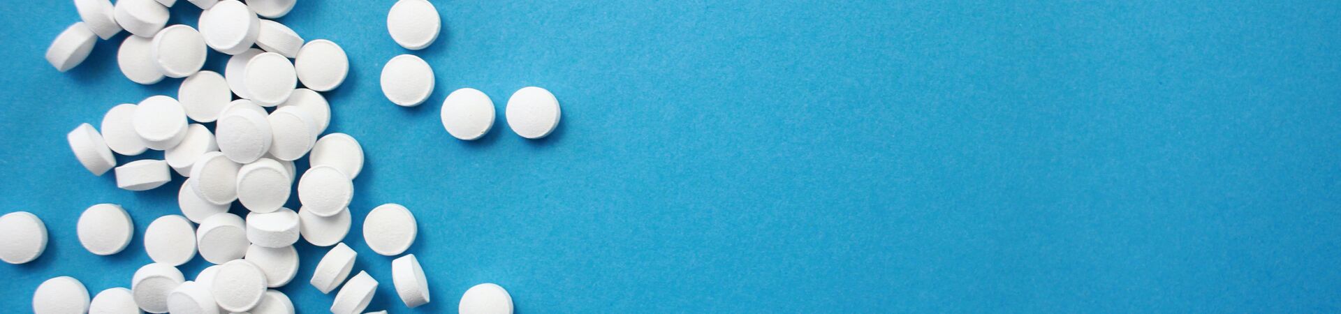 white pills scattered on a blue background
