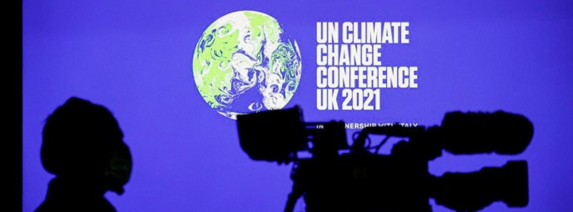 A cameraman sits in front of a screen displaying COP26 logo during a news conference at the UN Climate Change Conference (COP26), in Glasgow, Scotland, Britain, November 5, 2021. Photo : Reuters
