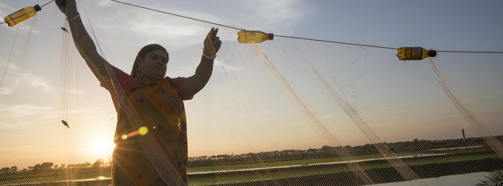 a woman with a fishing net near a pond