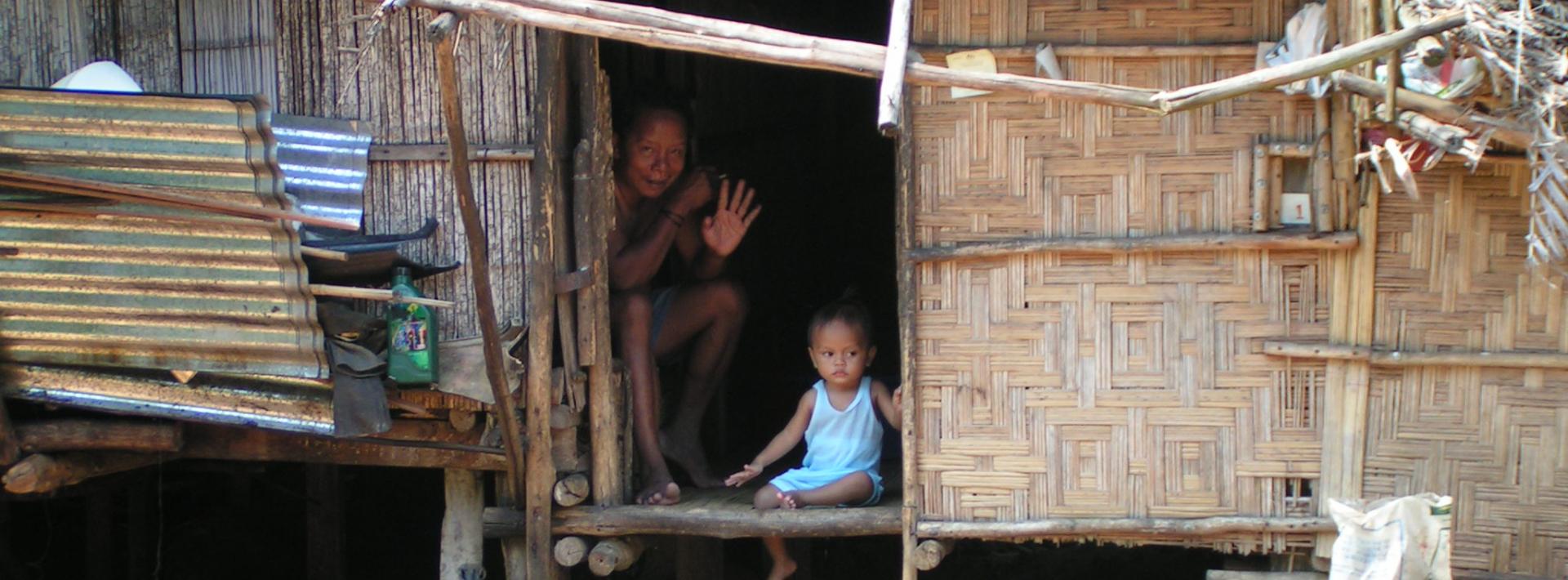 a woman and child inside a thatched hut
