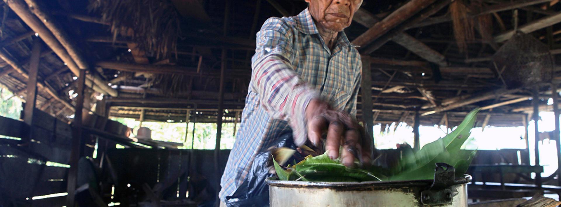 A man boils leaves over a large pot