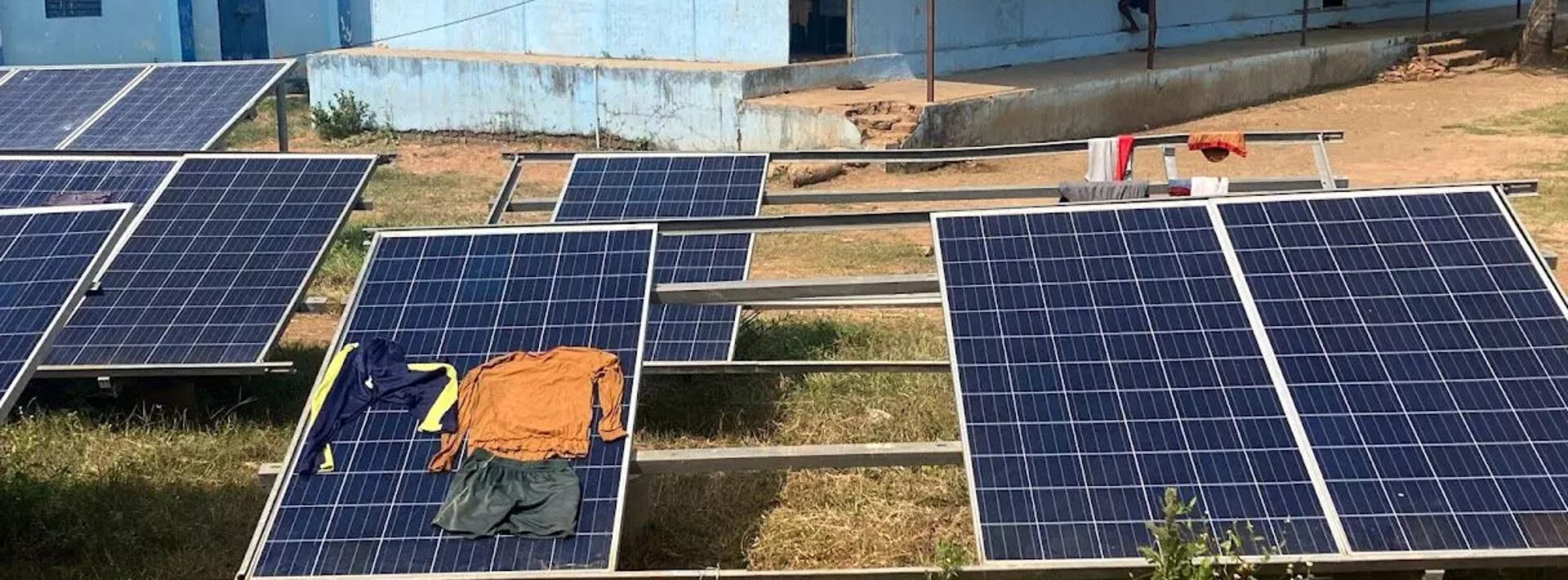 clothes drying on solar panel outdoors in front of blue building 