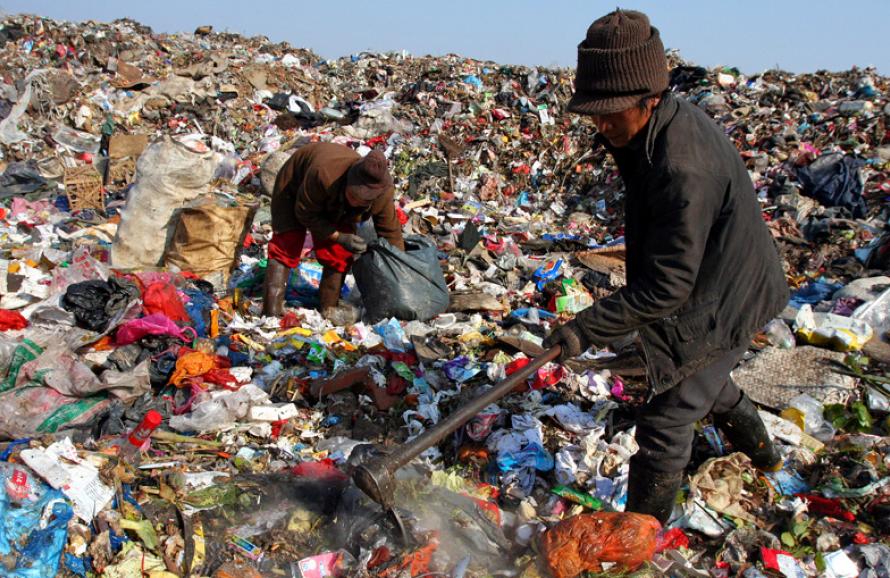 two people sorting through garbage in a landfill 