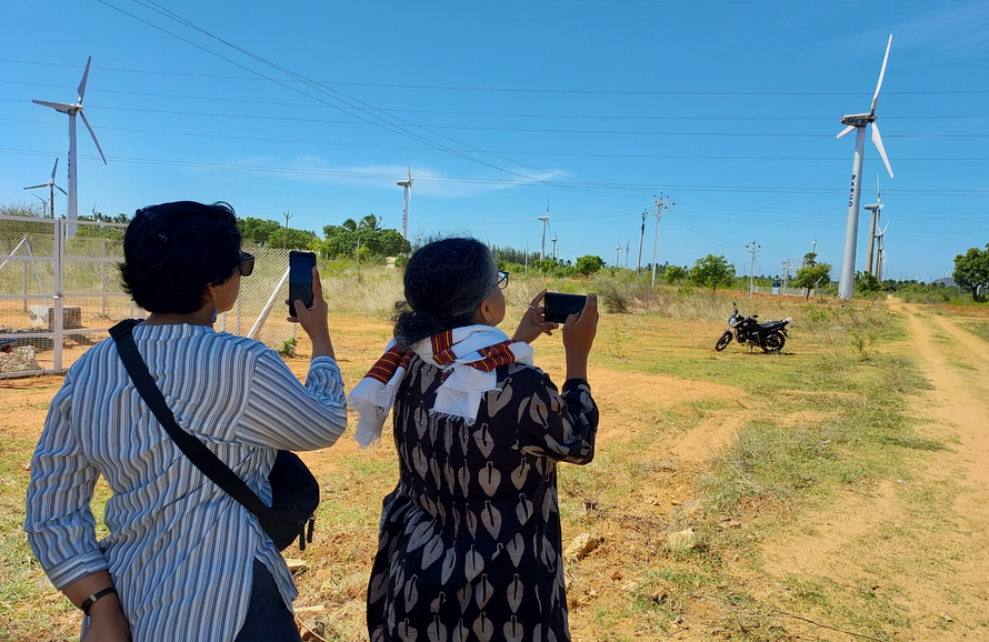 Two journalists photograph a wind turbine in Tamil Nadu