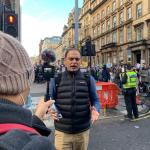 a journalist speaking into a microphone on the streets of Glasgow