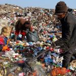 two people sorting through garbage in a landfill 