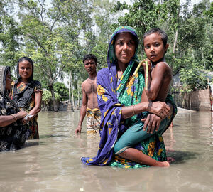 women with children standing in floodwater