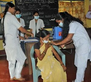 Woman in yellow sari receiving vaccination 