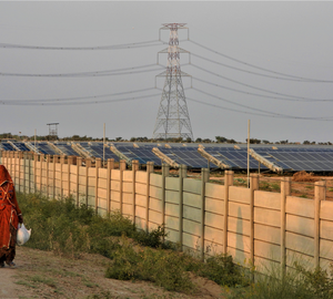 A woman walks along the fence of a solar plant near Gajner village in Rajasthan state on November 28, 2021