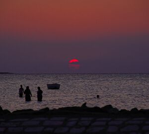 Sunset on the sea with 3 fishermen in the water
