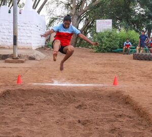 A woman athlete jumps into a pit of sand for training
