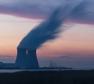 nuclear plant cooling tower emitting smoke at sunset