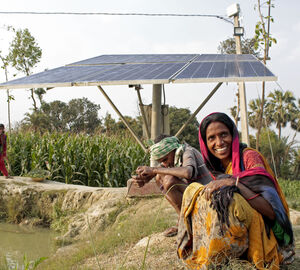 woman seated near an aquaculture pond with solar panels in background